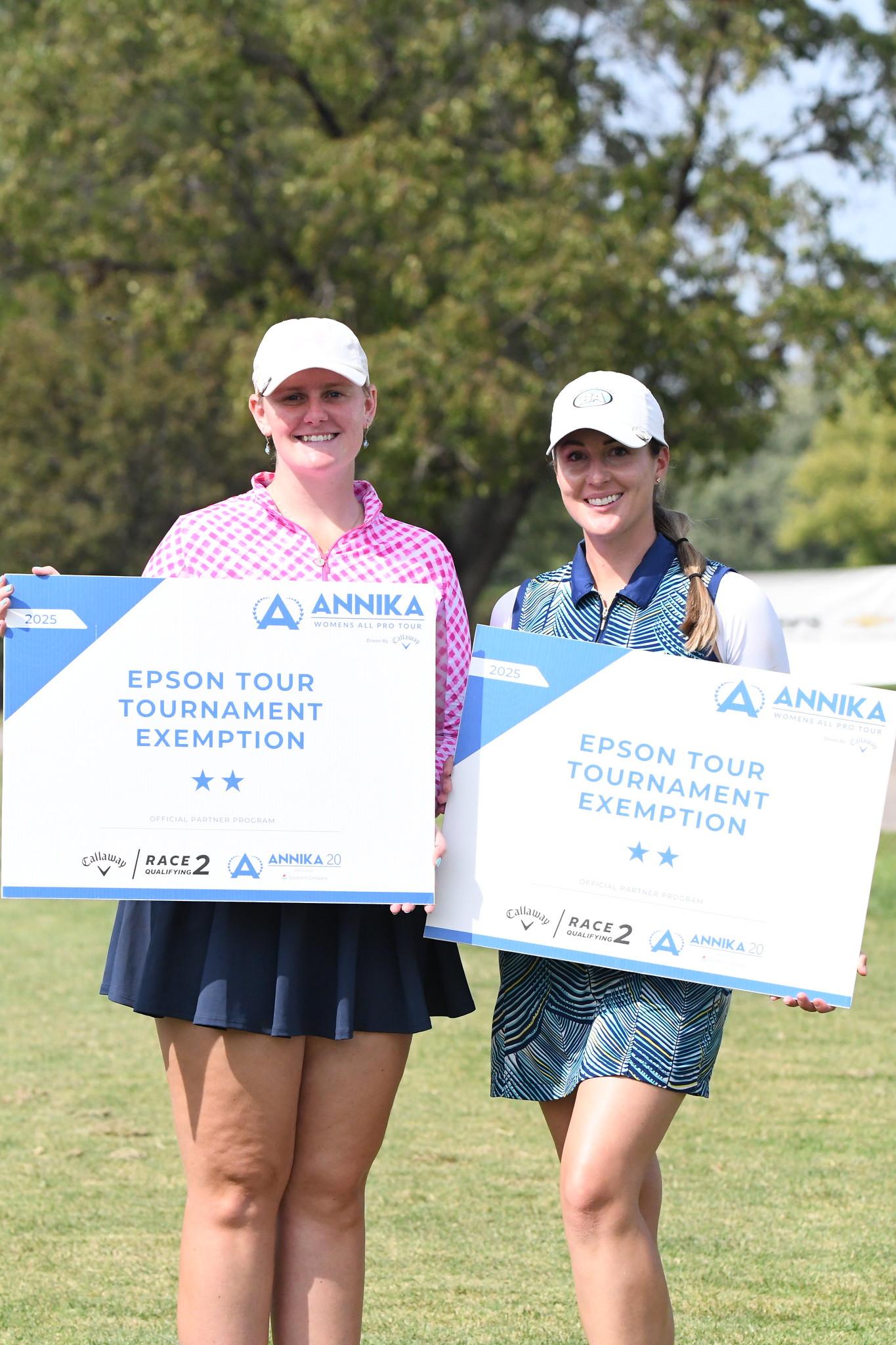 Two women in golf attire hold tournament exemption signs on a grassy area.