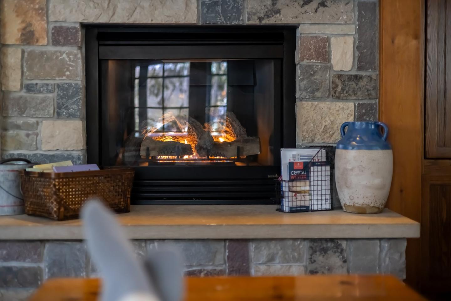 Cozy fireplace with a stone surround and nearby decor, viewed from a relaxed angle.