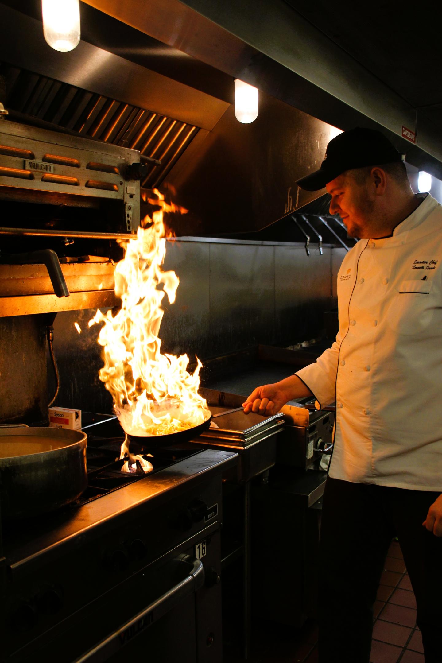 Chef cooking with flames in a restaurant kitchen.