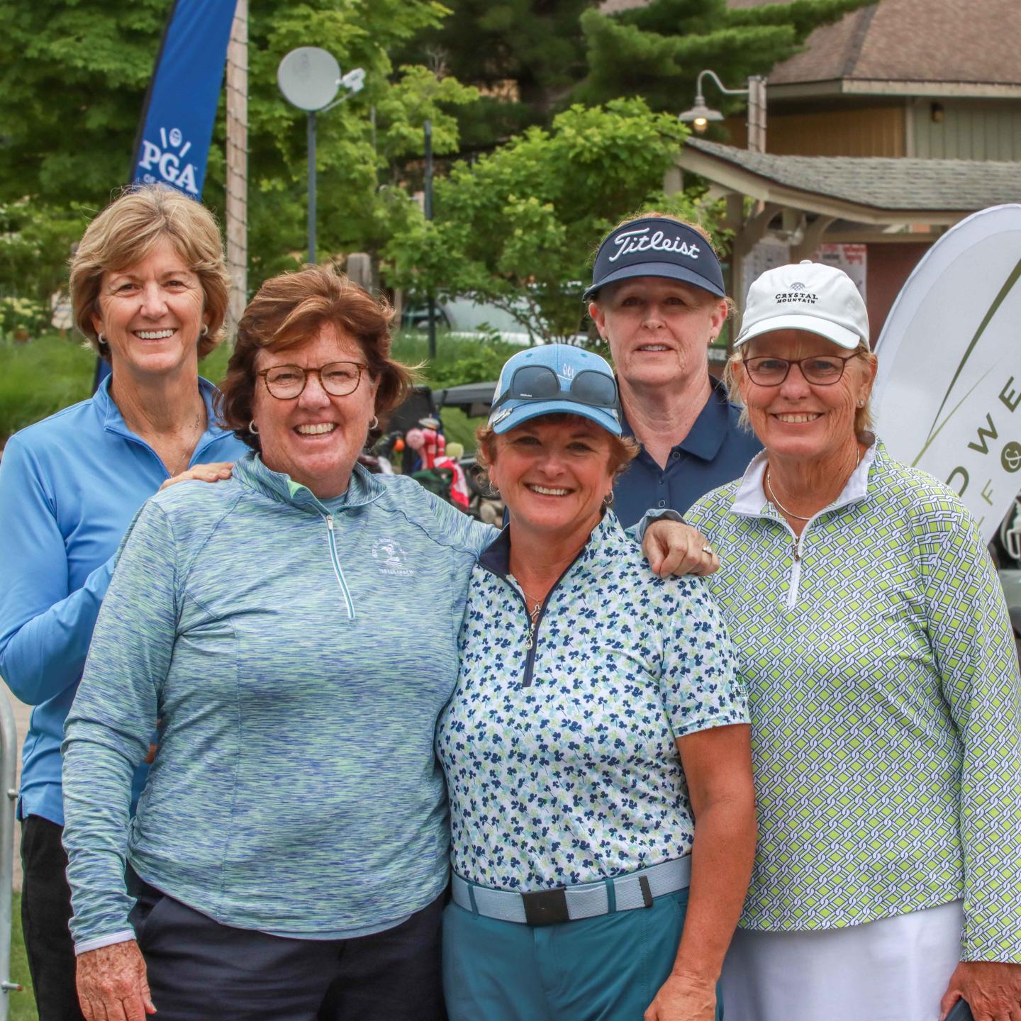 Five people smiling in golf attire outdoors.