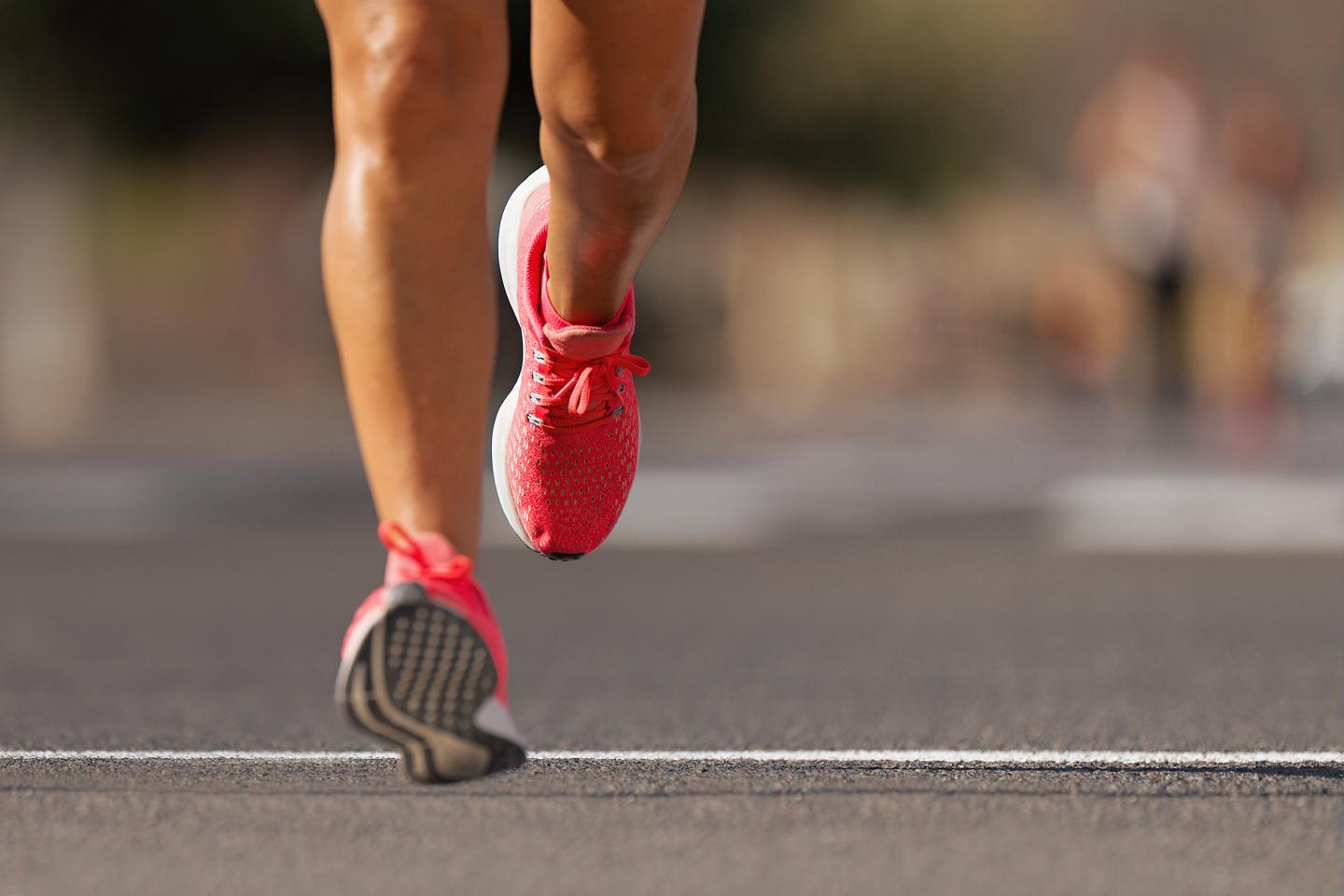 Runner in bright pink shoes on a road.