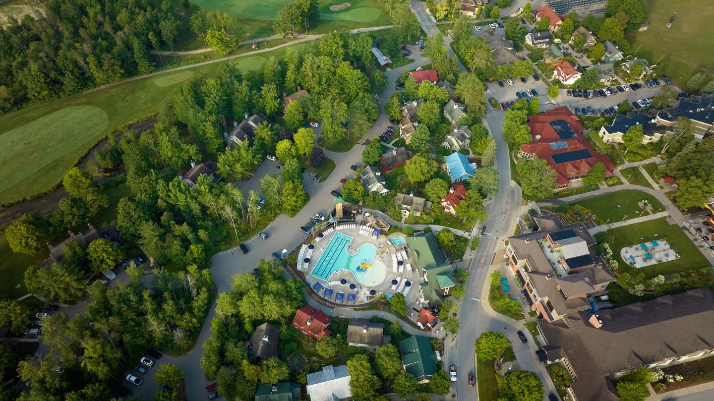 Aerial view of a park with a central pool, surrounded by trees and buildings.