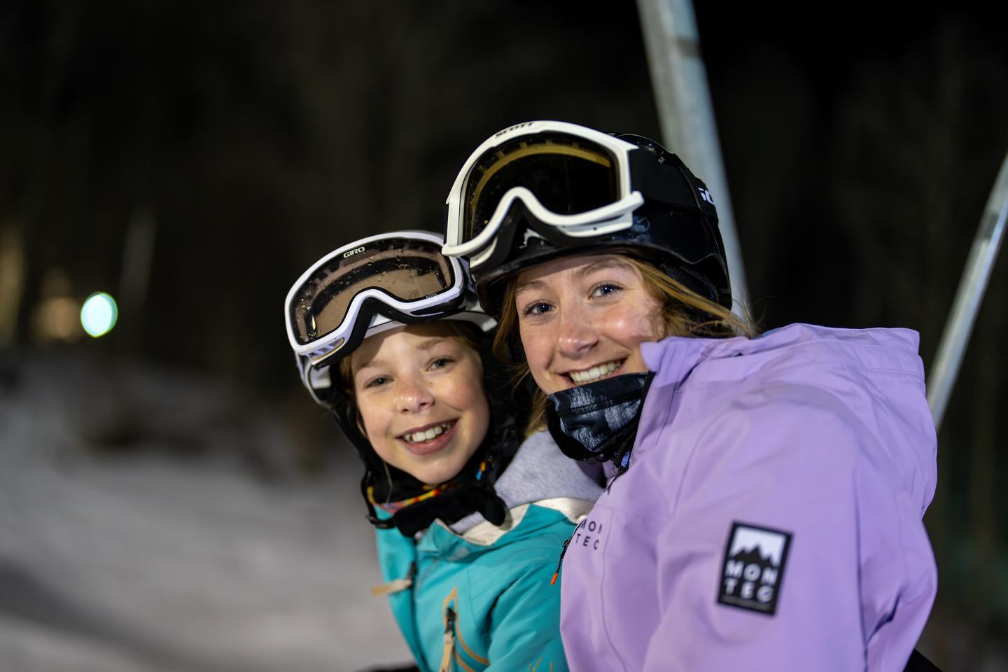 Two people in ski gear, smiling at night.