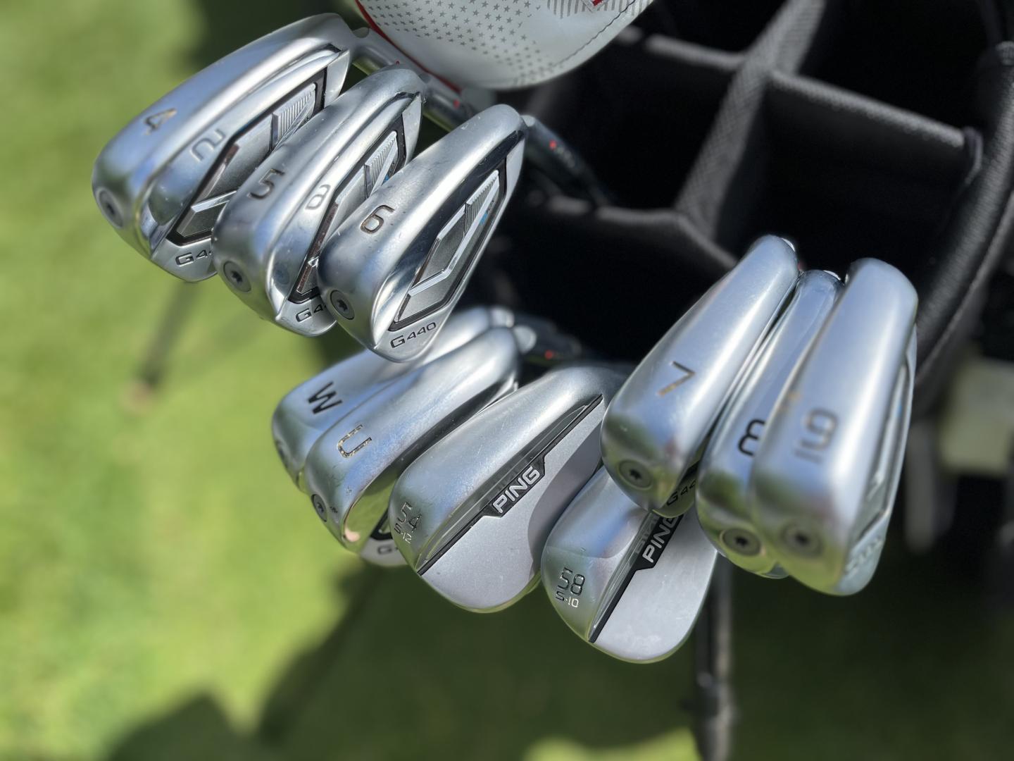 PING Golf clubs in a bag on a green lawn.