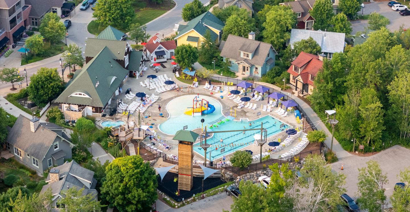 Aerial view of a colorful water park surrounded by trees and houses.