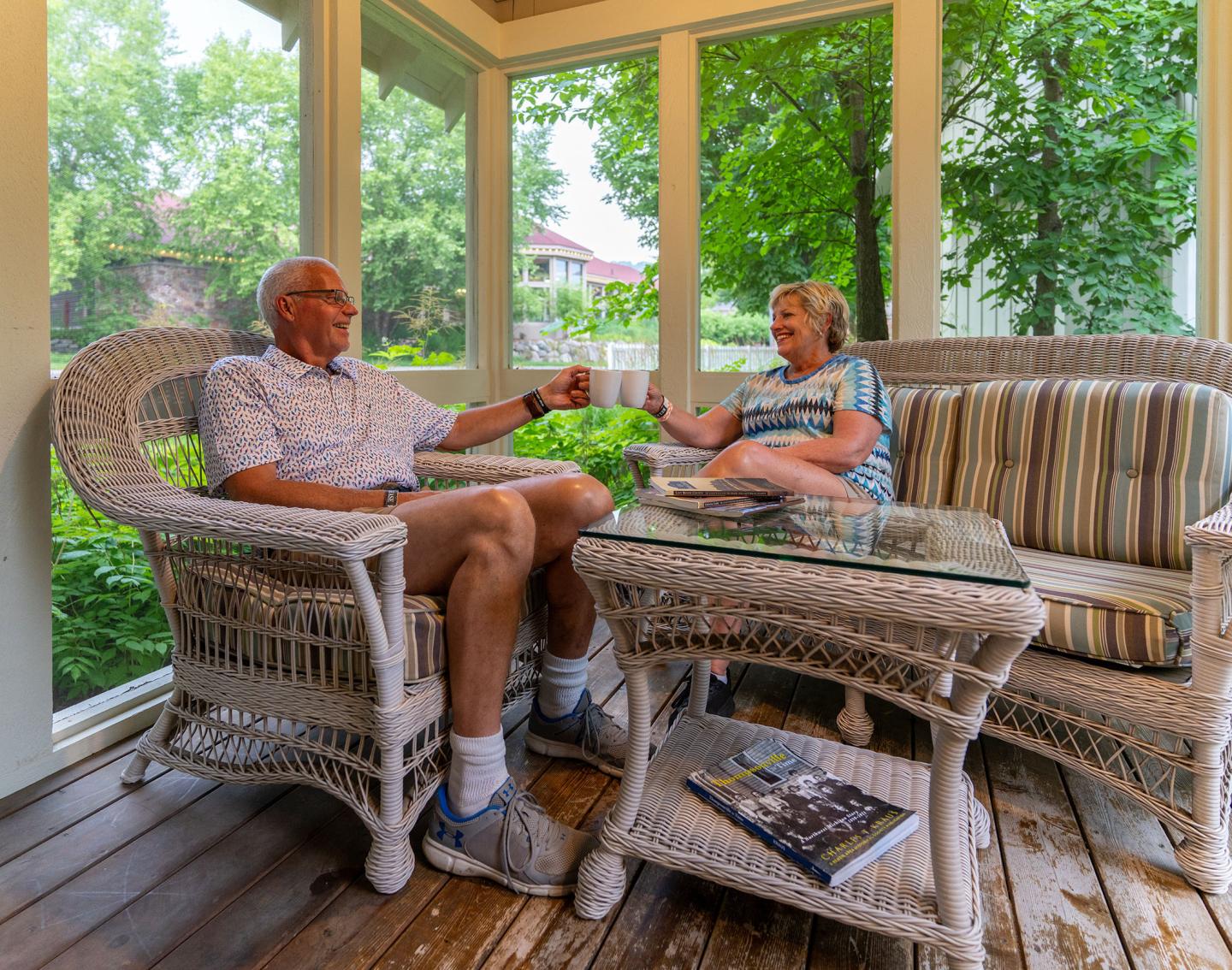 Older couple sitting in a sunroom, enjoying a conversation over coffee.
