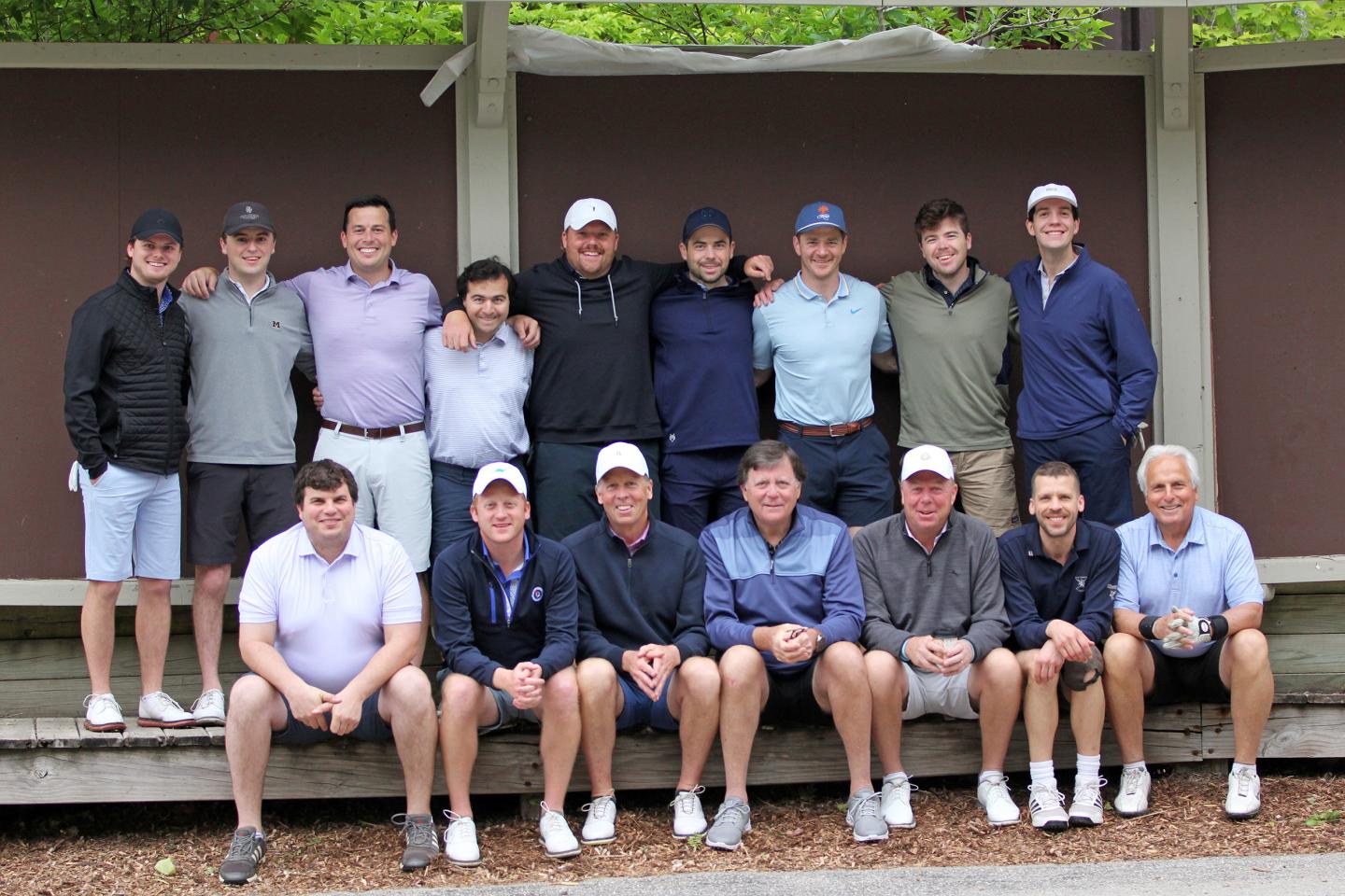 Group of men posing outdoors, wearing casual golf attire and caps.