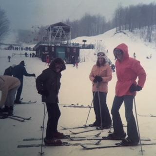 Skiers in colorful jackets pose on a snowy slope with a ski lodge in the background.