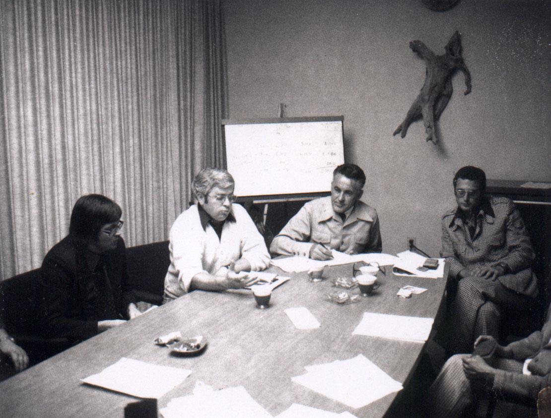 A group of people around a table in a meeting room, with notes and a flip chart.