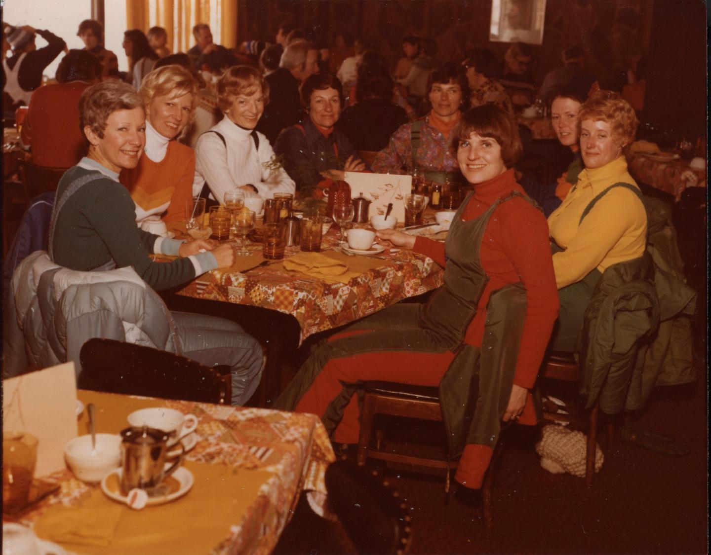 Group of women smiling at a table in a cozy restaurant.