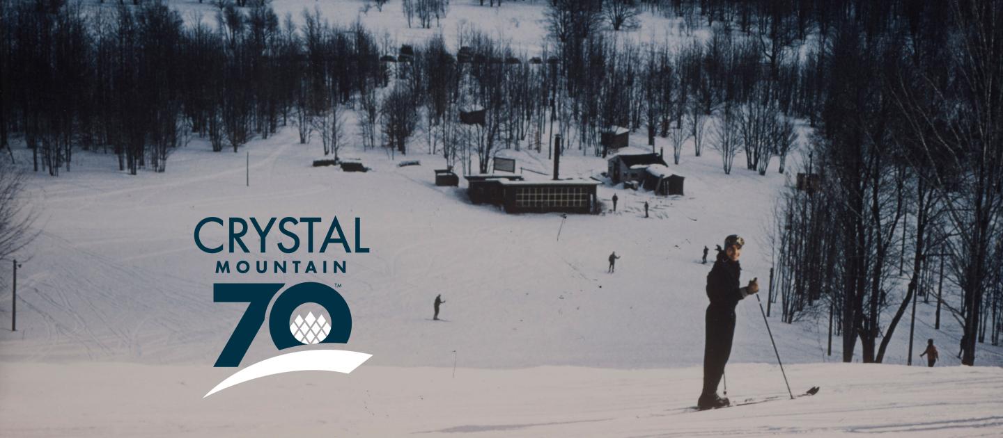 Snowy ski resort with a skier in the foreground and cabins in the background.