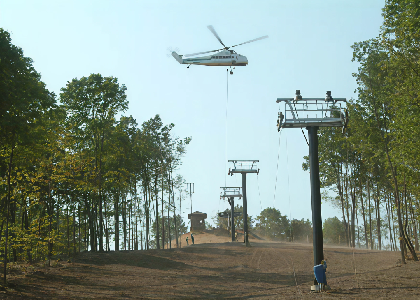 Helicopter lifting a structure near ski lift towers in a wooded area.