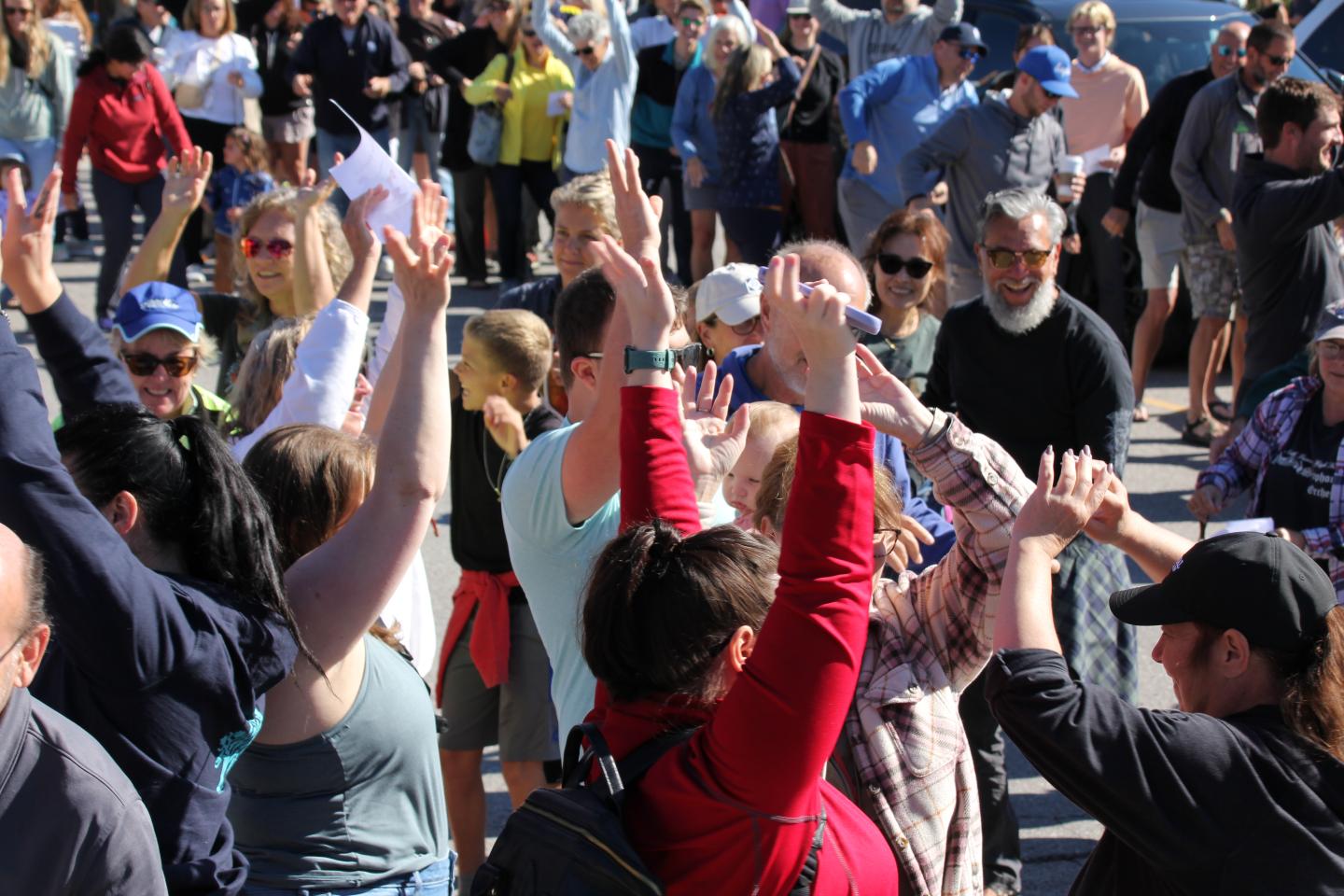 Group of people outdoors, raising hands in celebration.