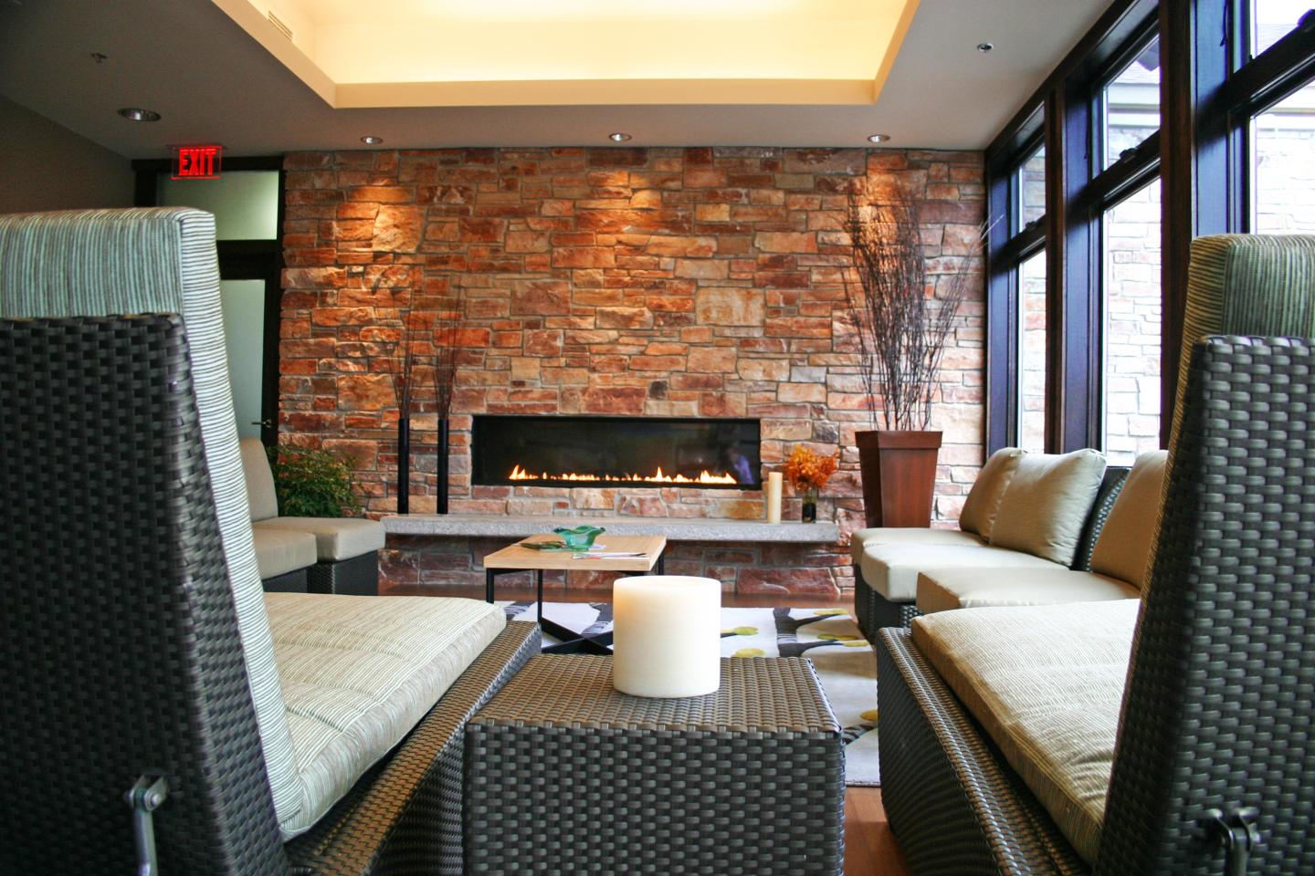 Cozy modern lounge with wicker seating, brick fireplace, and large windows